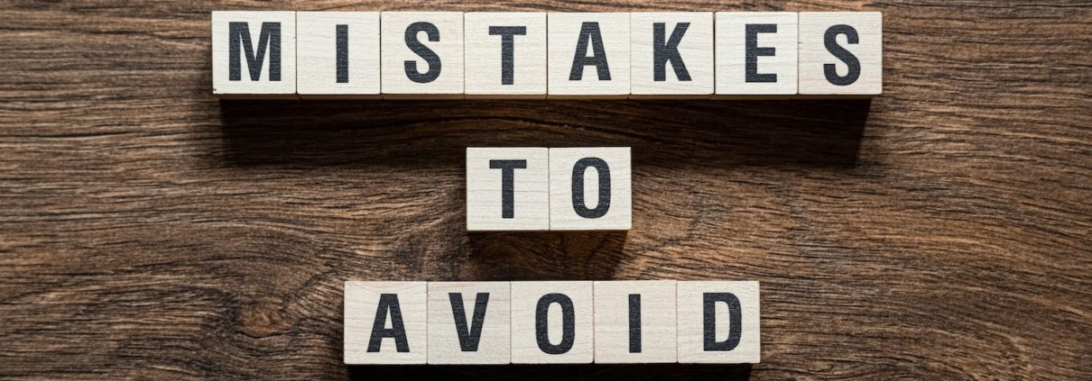 Wooden blocks spelling out 'Mistakes to Avoid' on a table, symbolizing the importance of strategies to avoid compliance mistakes in Title IV financial aid.