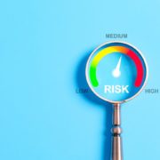 Magnifying glass highlighting a risk gauge with levels from low to high—needle pointing to medium risk. Visual concept representing audit readiness in financial aid operations.