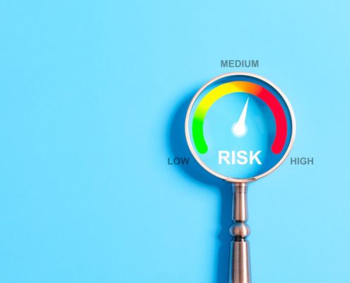 Magnifying glass highlighting a risk gauge with levels from low to high—needle pointing to medium risk. Visual concept representing audit readiness in financial aid operations.