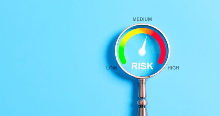 Magnifying glass highlighting a risk gauge with levels from low to high—needle pointing to medium risk. Visual concept representing audit readiness in financial aid operations.